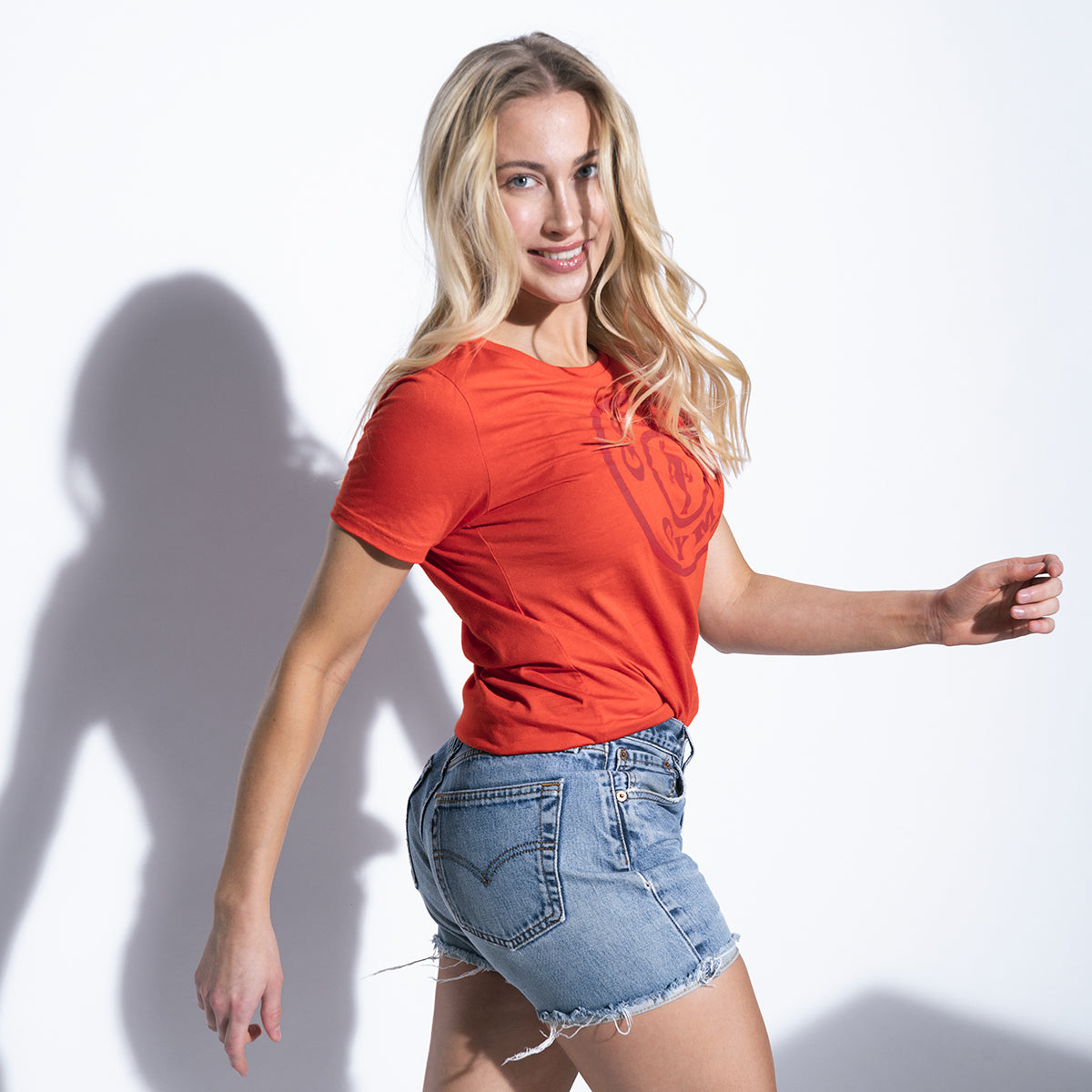 photo of female model wearing weight plate tee in red. large weight plate logo on front in darker red.
