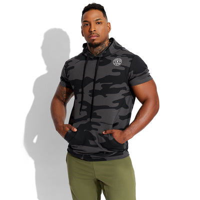 photo of male model posing wearing train short sleeve hoodie in black camo. golds gym weight plate logo in white on upper left chest.