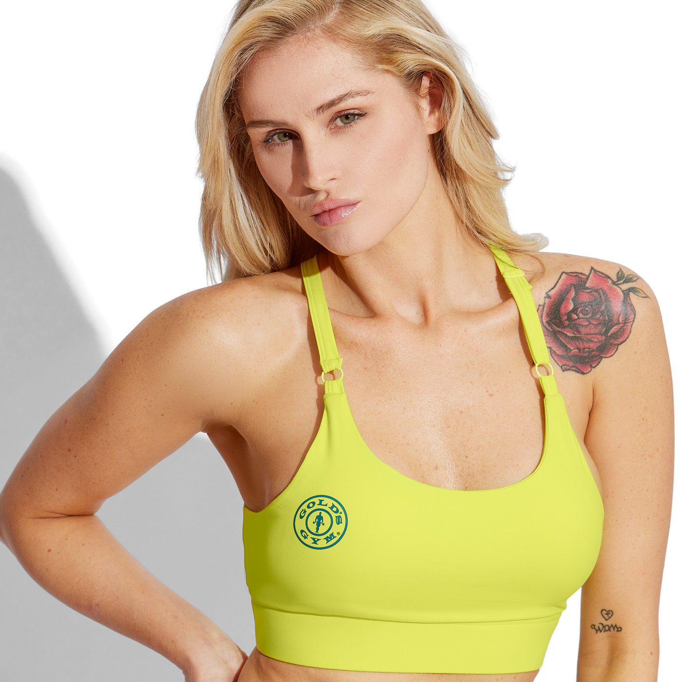 photo of female model wearing train bra in yellow golds gym weight plate logo in blue on right side.